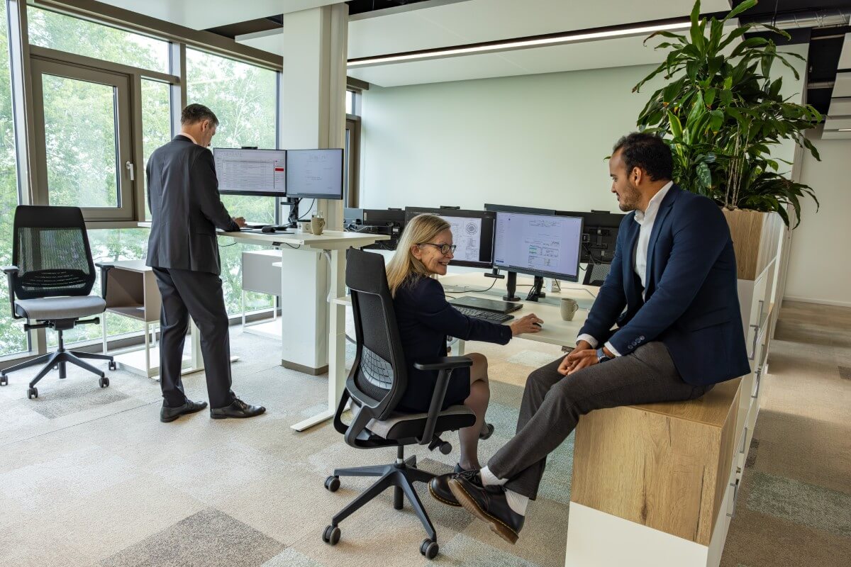 Kollegen sitzen zusammen in einem freundlichen Büro und unterhalten sich miteinander.