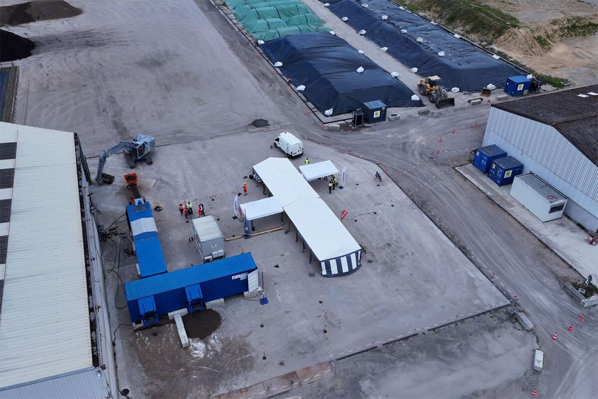 Luftaufnahme eines Industrieareals in Frankreich mit Zelten, Containern, Maschinen und abgedeckten Lagerflächen, im Rahmen eines Rückbauprojekts.