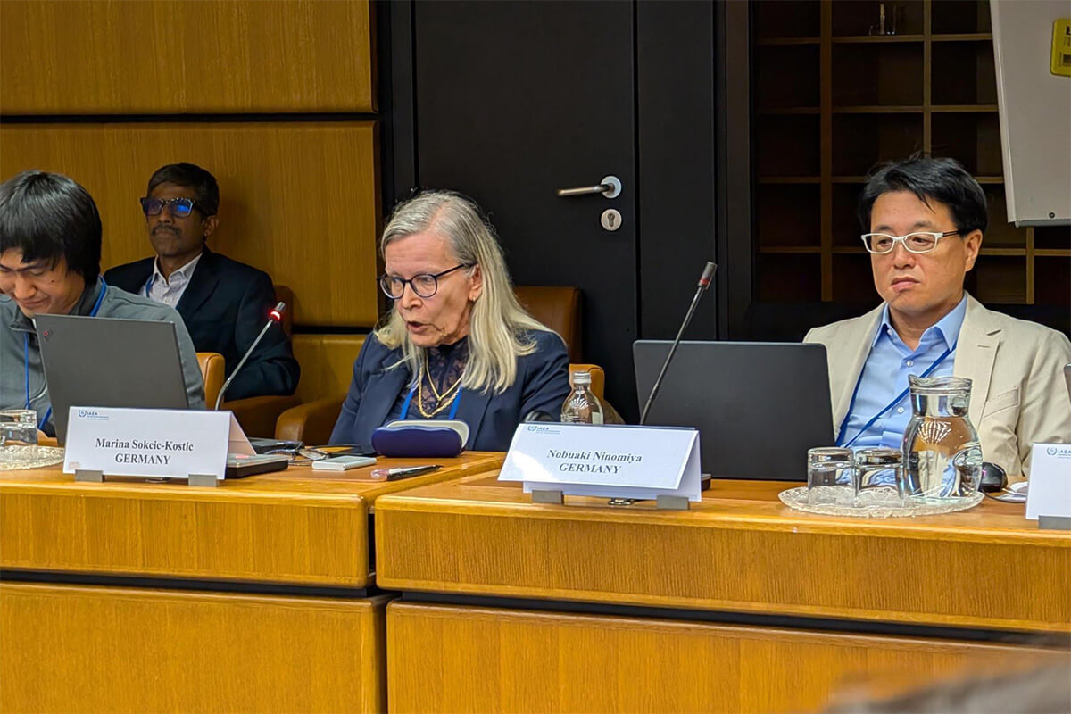 Nahaufnahme von Konferenzteilnehmenden bei der IAEA, darunter eine Frau aus Deutschland, die spricht, und ein Mann daneben mit Namensschild.